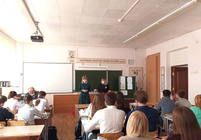 Две девушки стоят у доски перед классом 