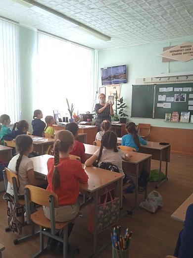 Девушка показывает книгу детям в классе