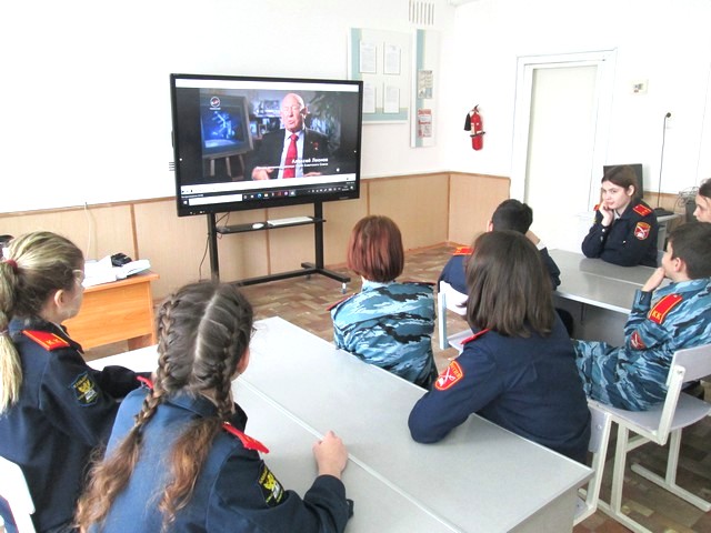 Дети в классе смотрят на работающий экран  телевизора 