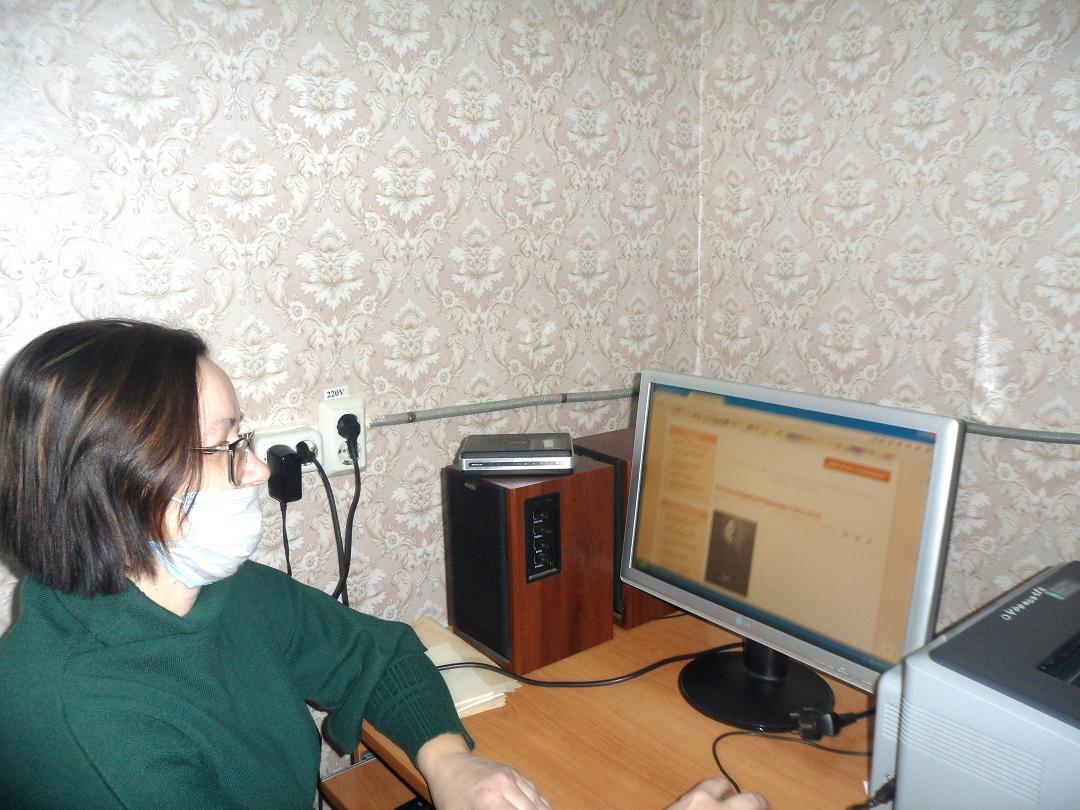 Девушка сидит перед работающим монитором компьютера 