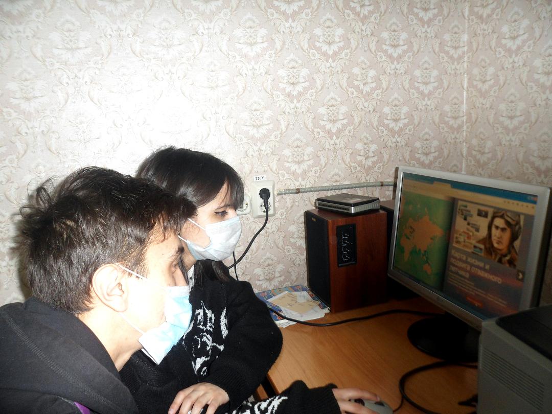 Двое молодых людей сидят перед монитором работающего компьютера 