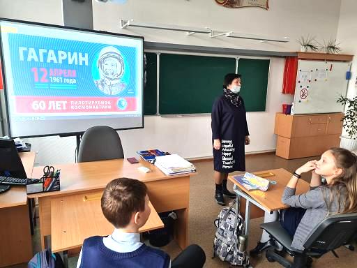 На экране портрет Гагарина и бибилотекарь стоит перед детьми в классе