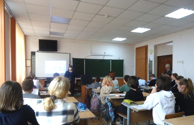 Стои бибилотекраь в классе и прововдит презентацию 