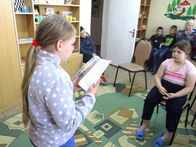 Девочка читает вслух отрывок из книги детям