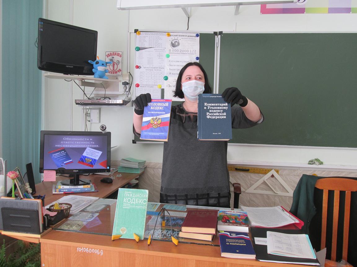 Стоит бибилотекарь в классе  и держит пред собой книги