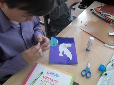 Ребенок  делает поделку из цветной бумаги