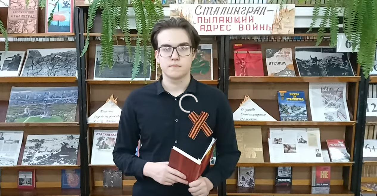юноша стоит с книгой в библиотеке