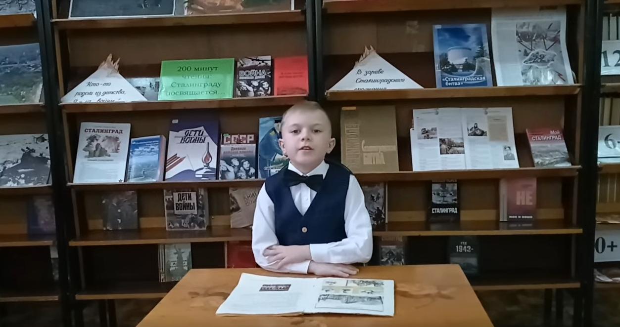 мальчик читает книгу в библиотеке