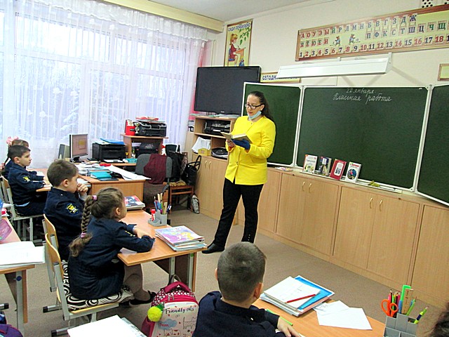 Библиотекарь читает детям книгу в классе